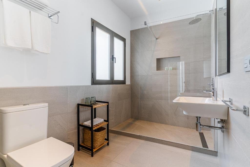 Baño amplio y luminoso con ducha moderna en habitación de Arena House Conil